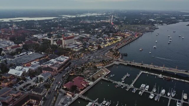 Aerial view captures St. Augustine's marina and city lights as twilight sets in. Ideal for travel documentaries or urban studies.