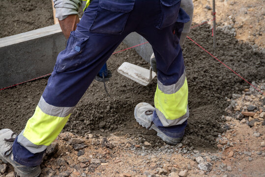 Worker leveling ground next to concrete curb The Concept of foundation and preparation