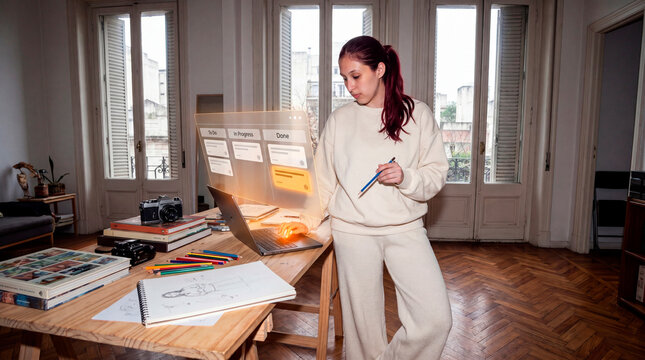 Focused creative professional managing digital workflow planning in home studio workspace