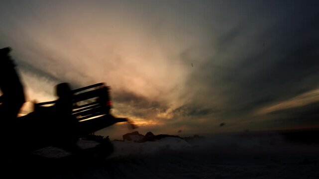 Silhouette of person jumping on snowmobile at sunset in mountains, dynamic winter action scene with motion blur, extreme outdoor adventure concept.