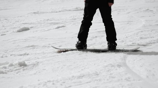 Close up of snowboarder slowly riding down snowy slope, beginner technique and smooth movement on snow, winter sport activity detail.
