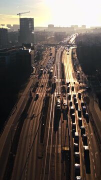 Public transportation tram moving city traffic bridge aerial sunset. Urban commute passenger rail vehicle road congestion golden hour light. Modern metropolitan infrastructure transport