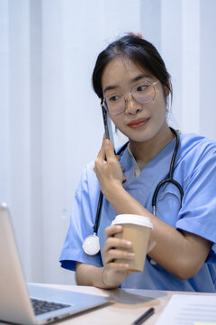 Medical professional in scrubs talking on smartphone while working at office desk