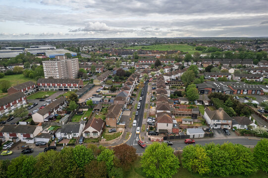Aerial view of rows of houses and buildings interspersed with lush greenery under a cloudy sky, Slade green, United Kingdom.