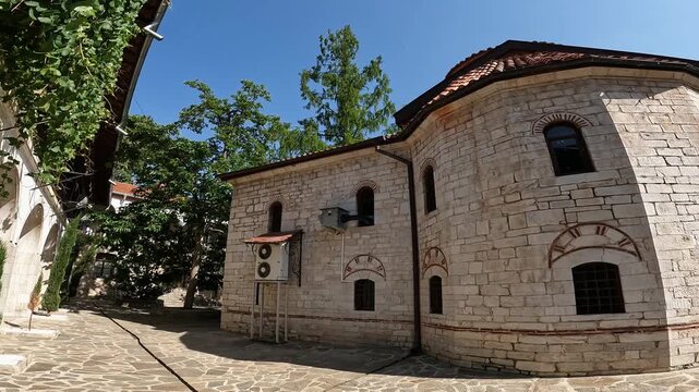 Handheld summer 2023 video with smooth panning motion capturing Bachkovo Monastery, showcasing its historic architecture, courtyard, and serene atmosphere in the Rhodope Mountains