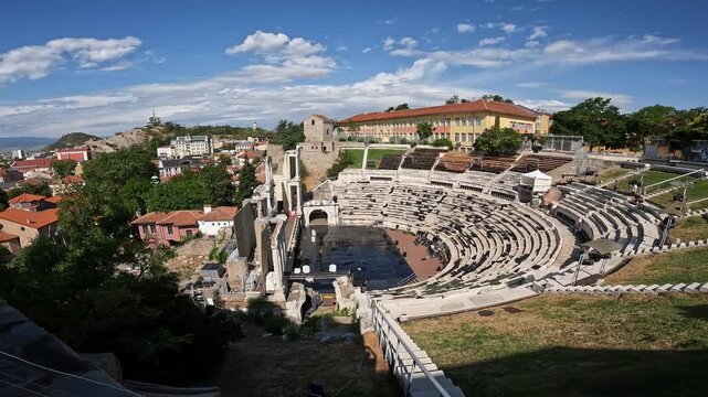 Handheld summer video with panning motion showing the Ancient Theatre of Philippopolis in Plovdiv, with surrounding hills and historic architecture in daylight. 2023