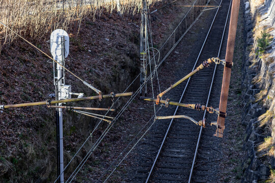 A high view of a railway catenary system featuring overhead wires and metal support structures along the track, representing modern rail infrastructure, logistics connectivity, and efficient transport