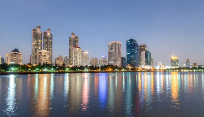 Obraz premium Modern city skyline at dusk with colorful waterfront reflections.