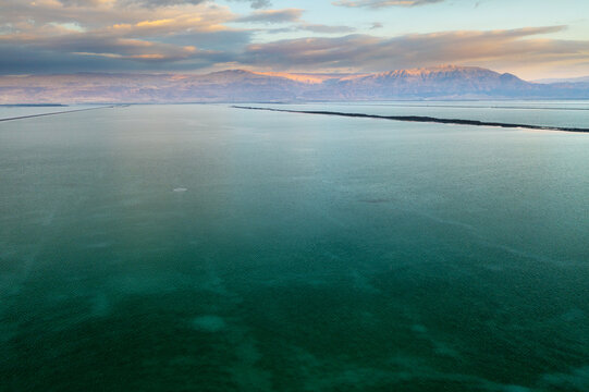 Aerial view of the vast expanse of the Dead Sea reflects the pastel hues of the dawn sky over distant mountains, Arad, Israel.