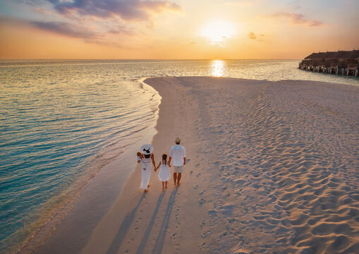 Aerial view of a beautiful family of four walking on a beach in the tropical Maldives islands during sunset time