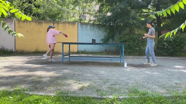 Outdoor sport - two Women Engage In Lively Table Tennis Game