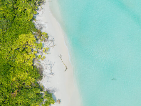 Aerial view of lush emerald foliage meeting pristine white sands and tranquil turquoise waters, Thuraakunu, Thiladhunmathee Uthuruburi, Maldives.