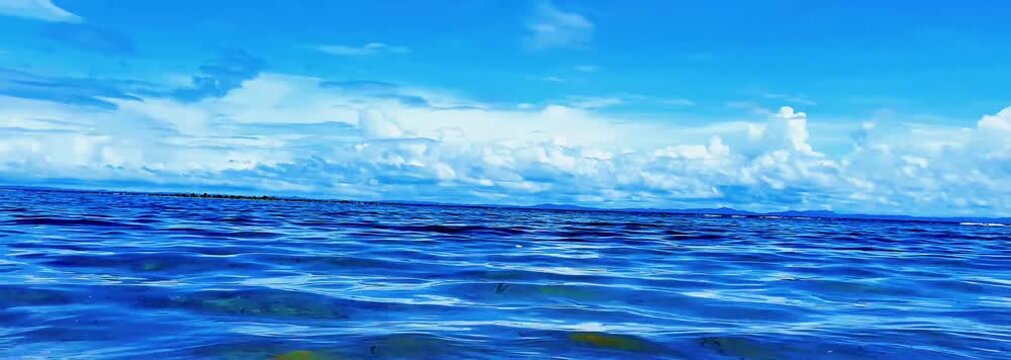 Calm ocean surface with gentle waves and dramatic cloud formation under blue sky