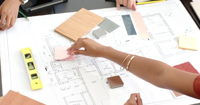 Diverse female team placing pink swatch comparing plan, using tablet at studio choosing colors