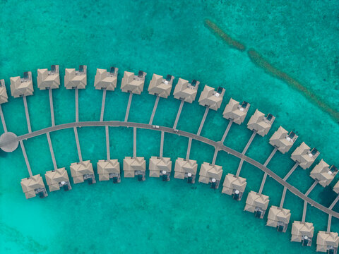 Aerial view of overwater bungalows stretch out into the turquoise ocean, their thatched roofs a stark contrast to the vibrant water, Hoarafushi, Thiladhunmathee Uthuruburi, Maldives.