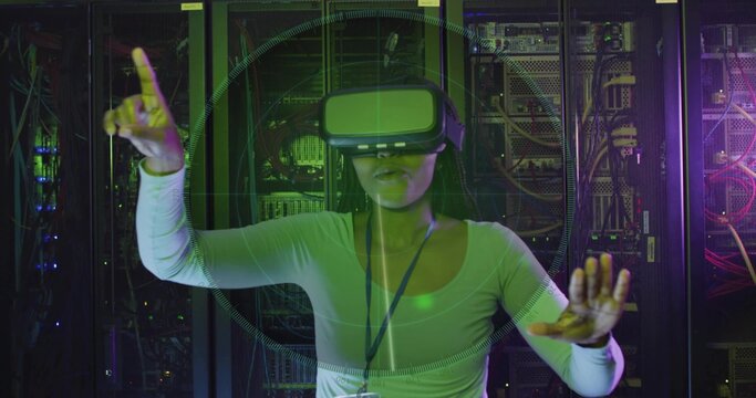 Interacting woman wearing VR headset, lanyard badge and long-sleeve top using HUD in server racks