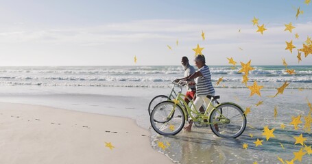 Fototapeta premium Walking pair pushing green bikes on beach barefoot prints waves gold-star overlay, copy space