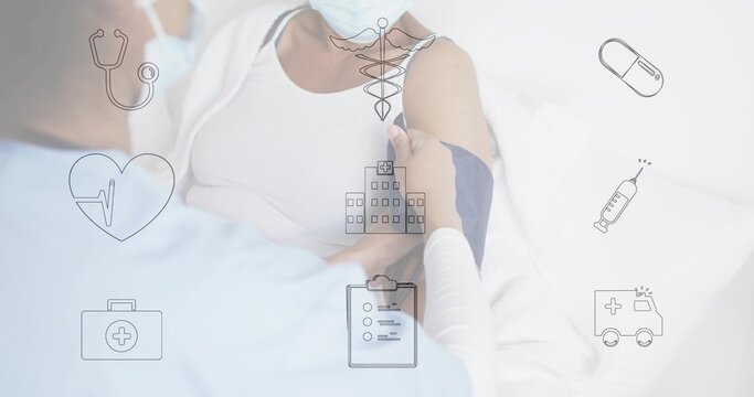 Checking nurse in blue scrubs mask measuring patient blood pressure at bedside with cuff and icons
