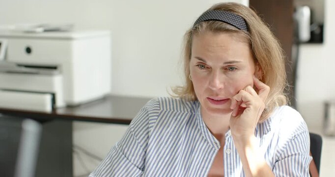 Woman sitting at desk reading screen then sitting upright and stretching overhead for relief