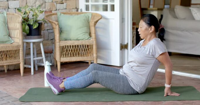 Senior female starting with hands planted, performing leg lifts into hamstring stretch on patio mat