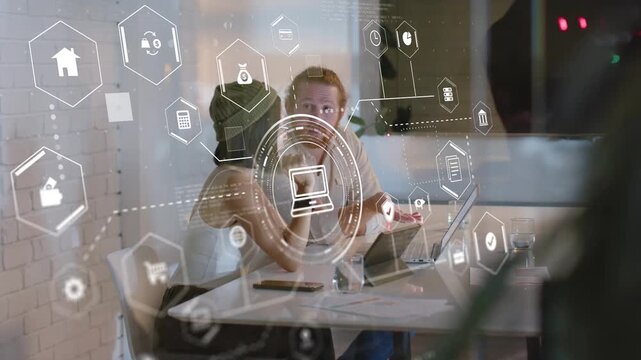 Man with man-bun pointing at laptop, colleagues bringing tablet, HUD overlay animating business
