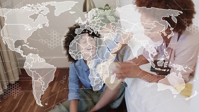Two women packing open suitcase in bedroom, planning travel and world-map overlay guiding folding