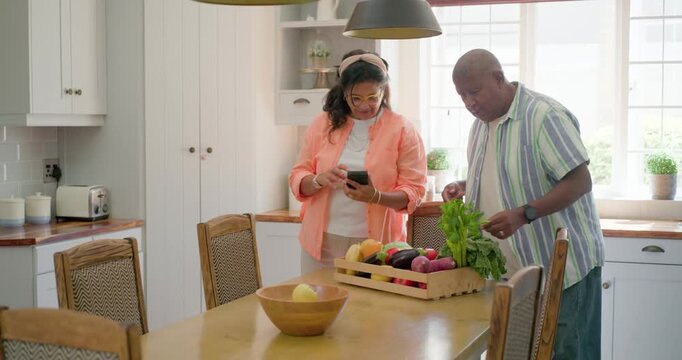 African American couple carrying wooden crate, sorting produce on kitchen table for meal prep
