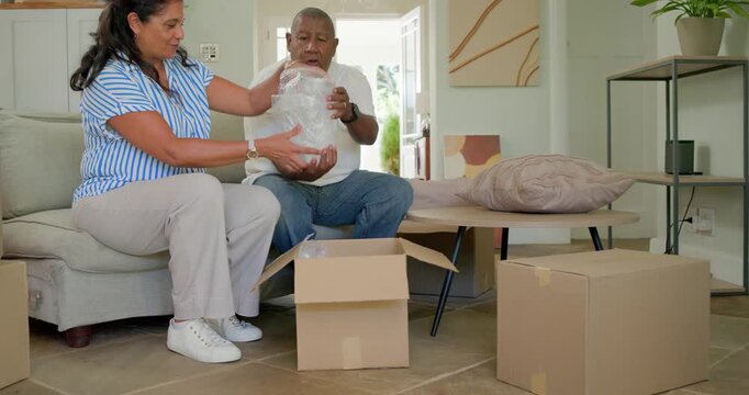 African American couple opening box peeling wrap lifting vase placing on table at home unpacking