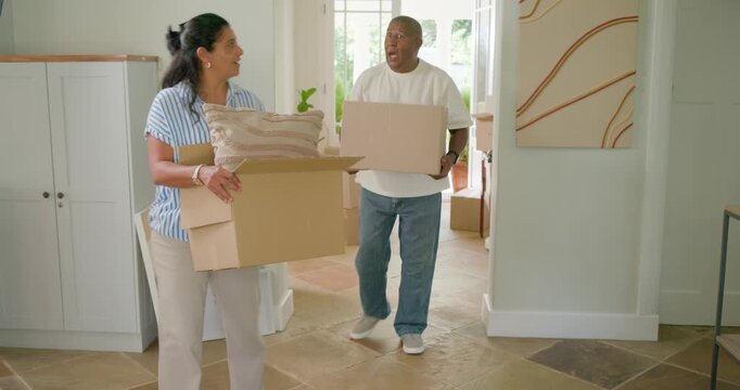 African American couple entering doorway carrying boxes, removing pillow, hugging, celebrating move