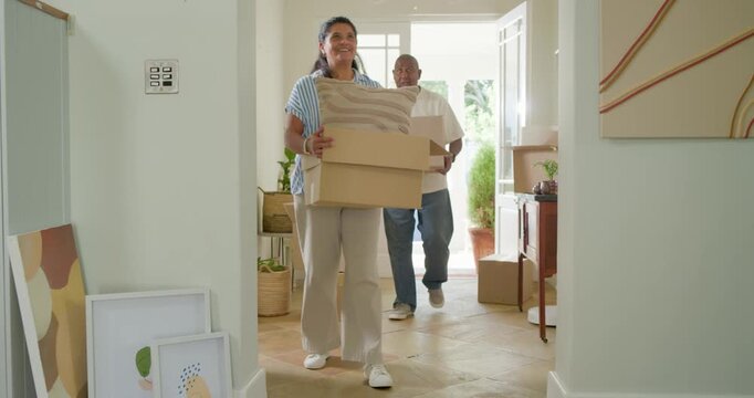 Front door opening leading African American couple carrying boxes and cushion into foyer, moving in