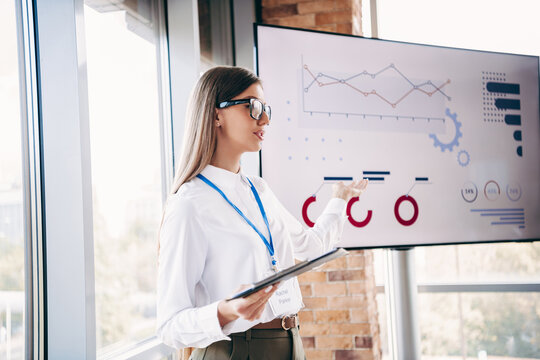 Business presentation by a confident female presenter showing data charts and analytics on a screen in a modern office meeting room