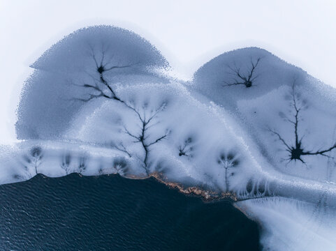 Landscape, tourism: Aerial view of frozen lake with ice patterns resembling trees, winter environment, Fusine lakes, Tarvisio, Friuli, Italy.