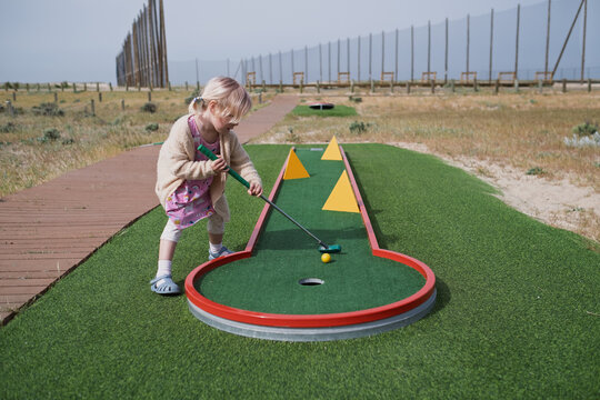 young Golfer in Training: Girl Practicing her Putting Skills on an Urban Mini-Golf Course