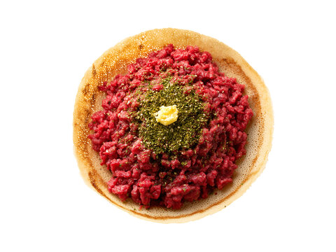 Fresh raw kitfo ground beef served on traditional ethiopian injera flatbread with butter and spices presented from a top view angle on transparent background