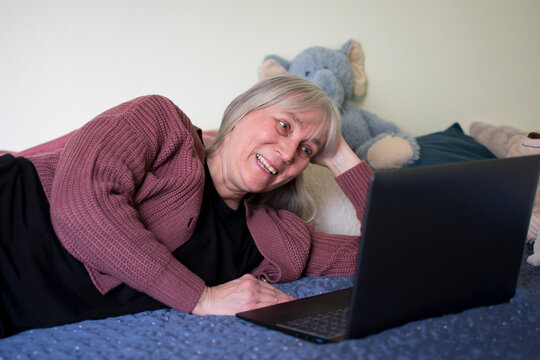 Mature woman laughing while watching laptop during video call at home