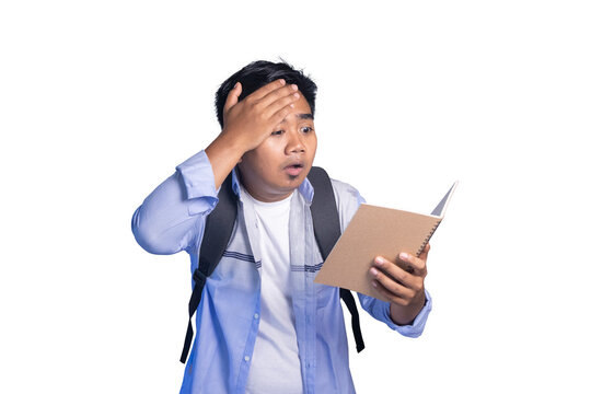 Confused male student holding a notebook while touching his forehead in shock, wearing a backpack on white background.