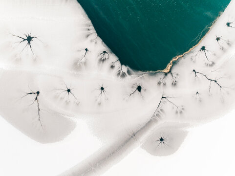 Landscape, aerial view of frozen lake with cracks and turquoise water, abstract nature pattern, destination concept. Fusine lakes, Tarvisio, Friuli, Italy.