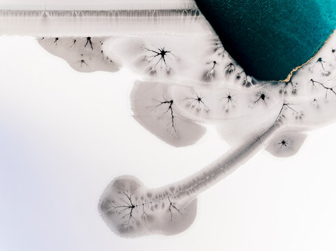Landscape, aerial view of frozen lake with cracks and turquoise water, abstract nature pattern, destination concept. Fusine lakes, Tarvisio, Friuli, Italy.
