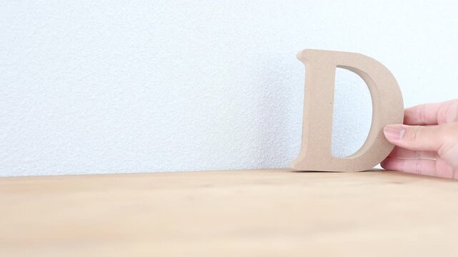 木製アルファベット文字D。木製テーブルの上に置く。