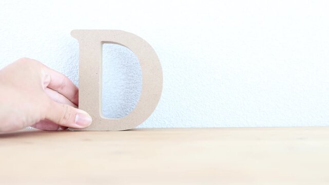 アルファベットのD。木製の文字を机の上に置く