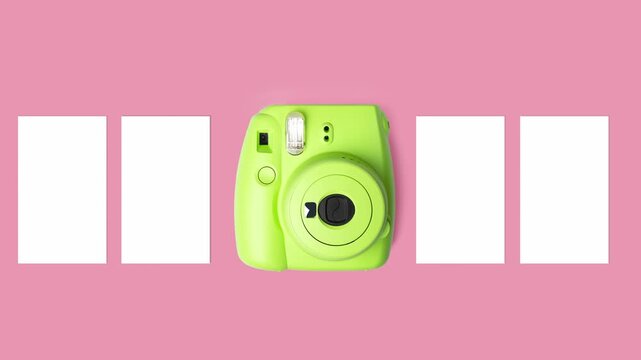 Bright green instant camera with blank photo prints on a pink background