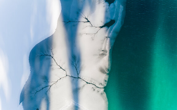 Aerial view of frozen lake with ice patterns and turquoise water, winter landscape, destination concept. Fusine lakes, Tarvisio, Friuli, Italy.