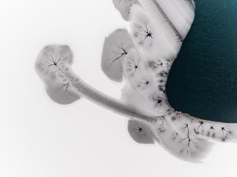 Winter landscape, aerial view of frozen lake with cracks, ice texture, nature background, Fusine lakes, Tarvisio, Friuli, Italy.