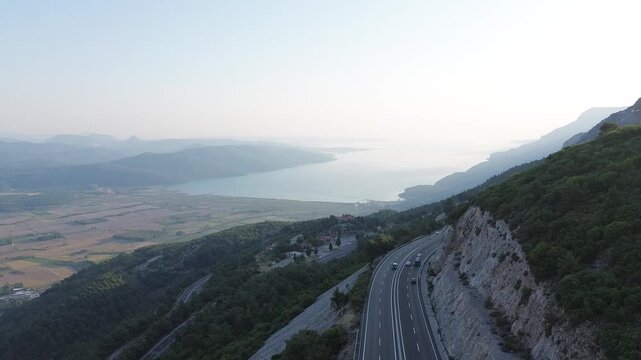 Cinematic transition from a sharp highway bend to a beautiful coastline and sea
