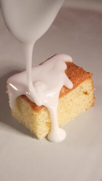 Vertical 4K Close Up of White Icing Pouring from Spoon onto Cake