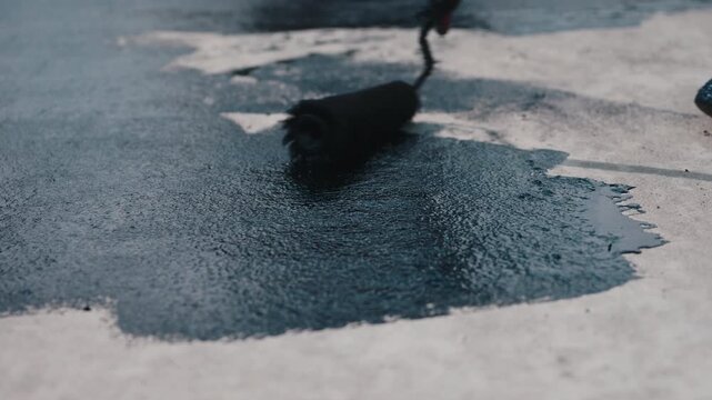 Applying bitumen primer on concrete surface before waterproofing close up