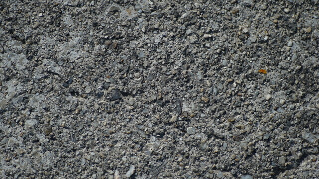 Detailed macro shot of weathered grey concrete pavement with small gravel aggregates