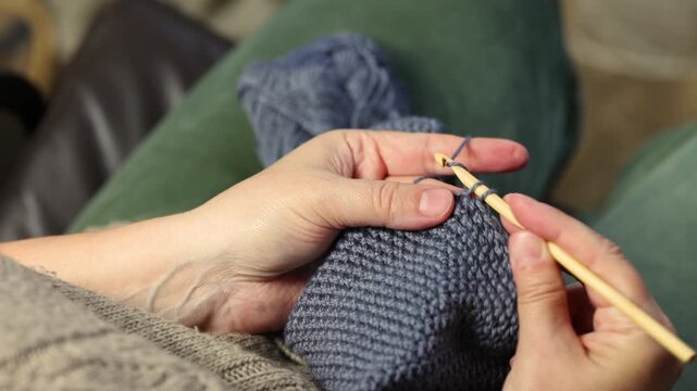 Woman crochets bag made of knitted grey threads. Engaging hobby