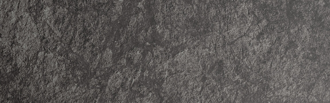 Dark gray slate background presenting a rough stone texture with a natural rocky surface, creating a rugged and weathered wall effect