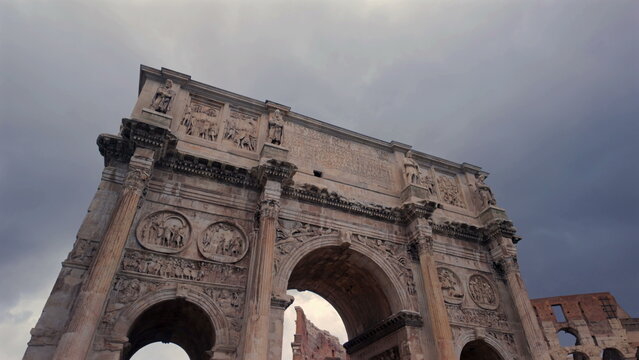 Arch of Constantine close-up with ornate reliefs and columns under stormy sky next to the Colosseum